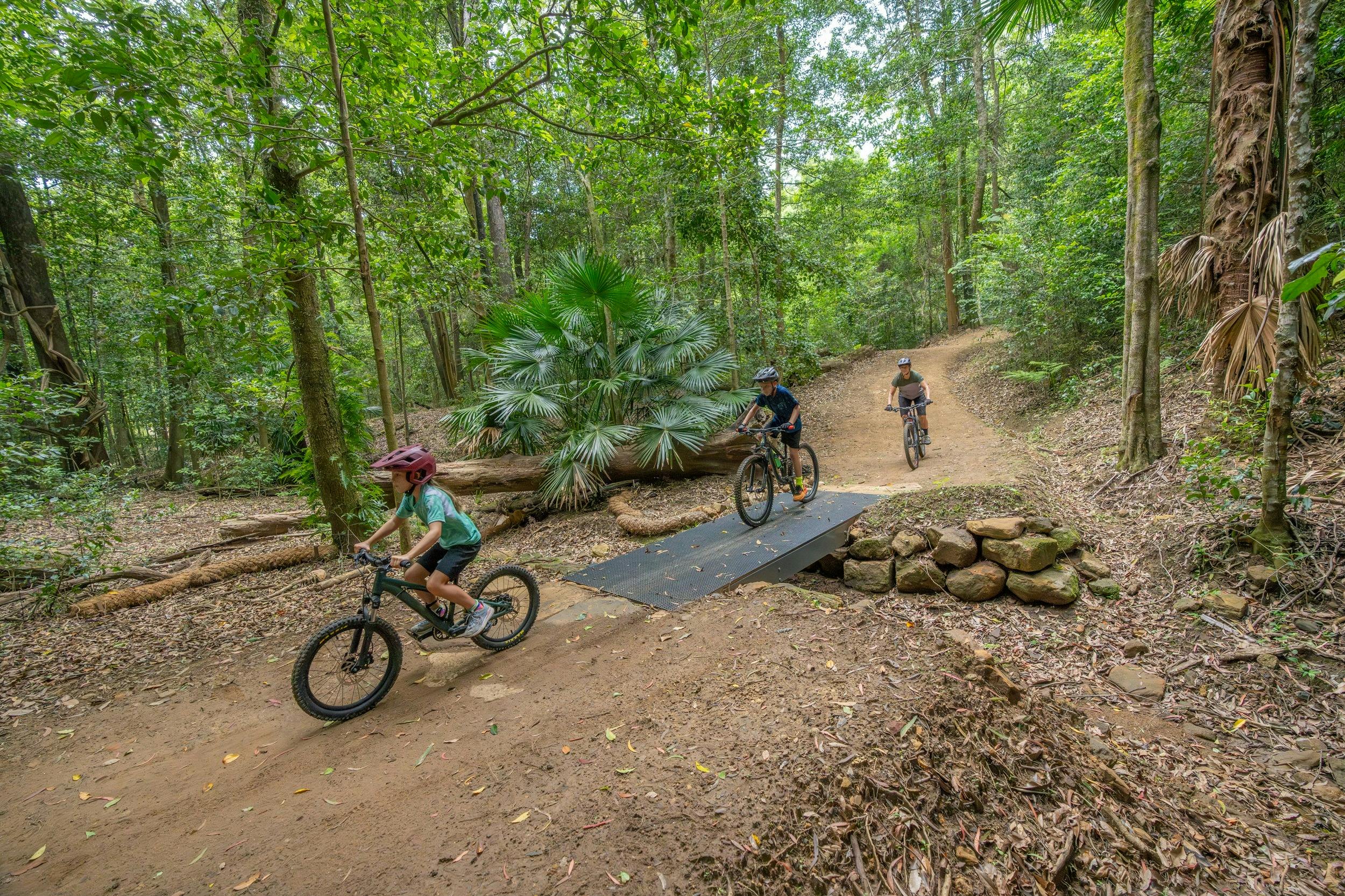 A family riding through the rainforest on Kembla mountain bike trails.