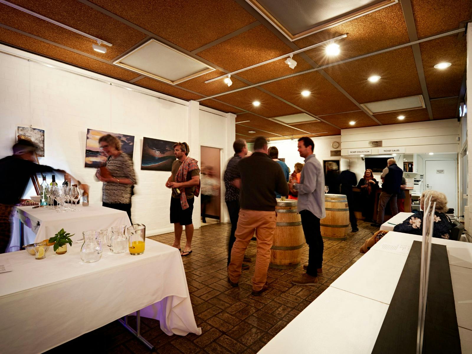 A server pours wine whilst patrons mingle in the foyer