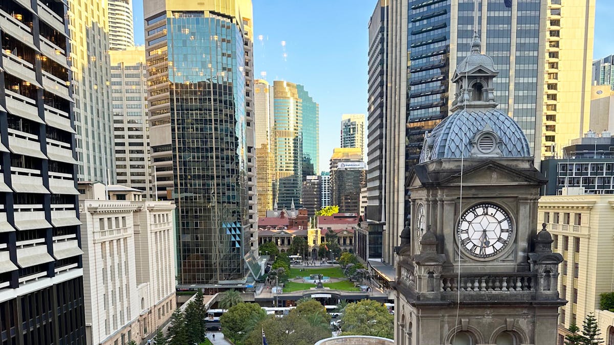 City high righes surrounding city park.  Clock tower in the front right
