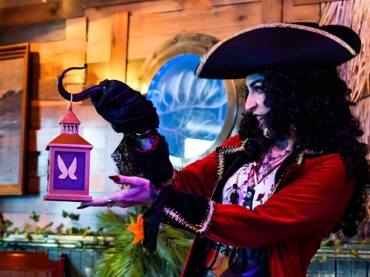 Actor playing Captain Hook holding a lantern on their hook