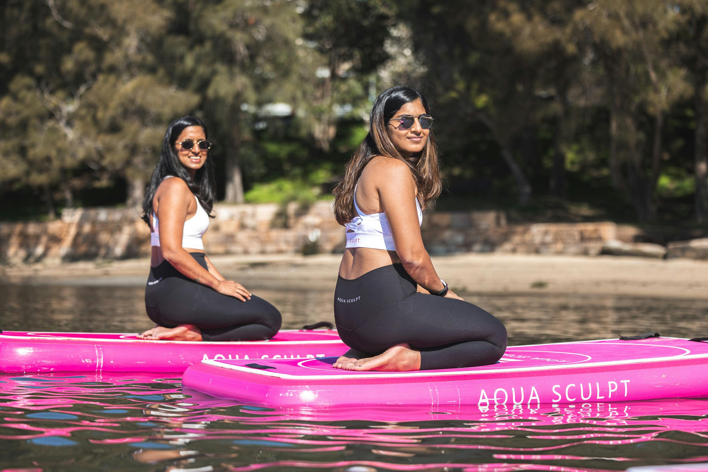 필라테스 수업이 시작되기를 기다리며 아쿠아 스컬프트 보드에 앉아 있는 두 자매