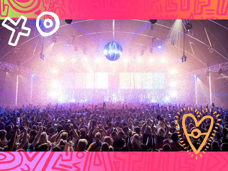 A photo of an indoor concert stage with a crowd in front  with flashing lights and a disco ball