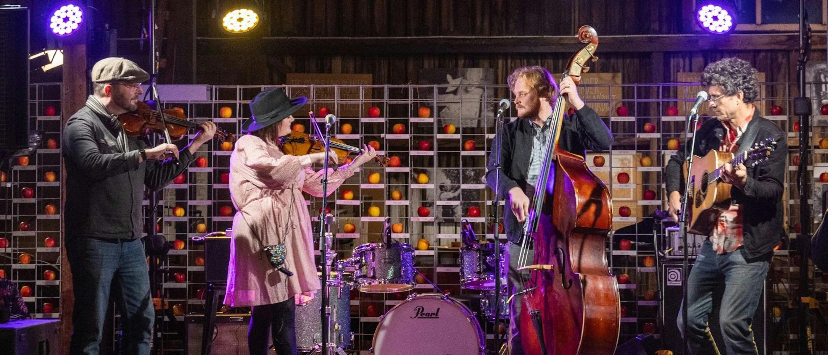 Four performers on a stage with musical instruments