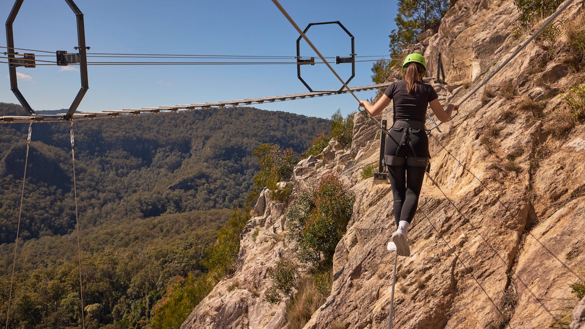 Woman walking across Via Ferrata at Happitat Adventure Park
