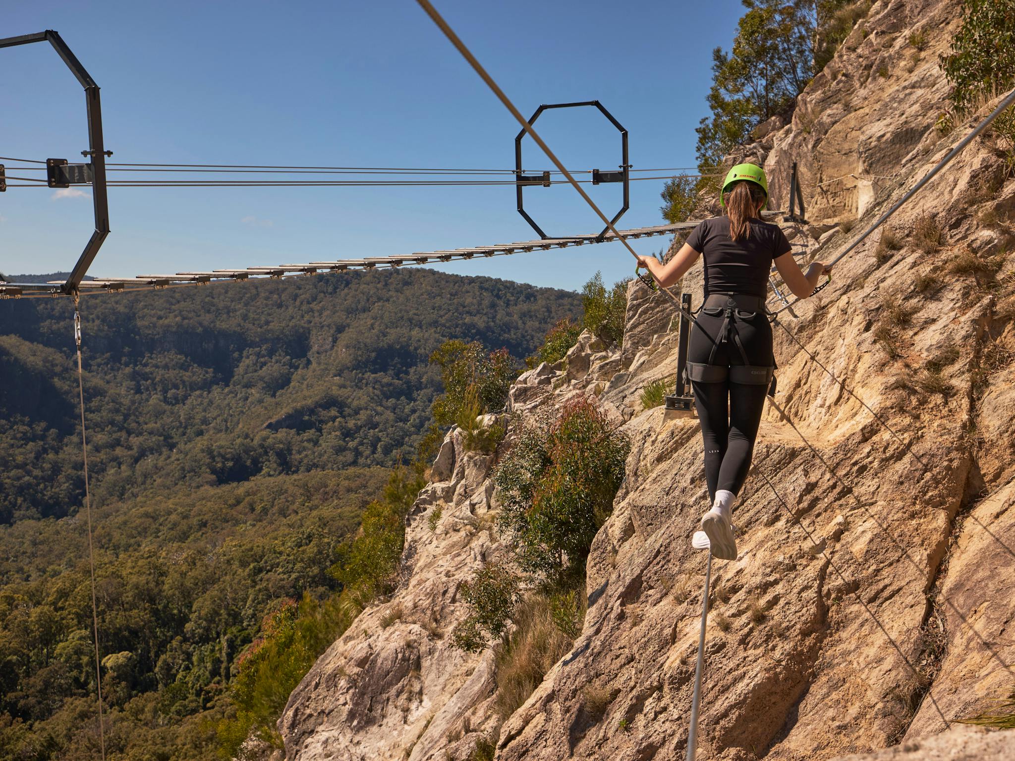Woman walking across Via Ferrata at Happitat Adventure Park Woman walking across Via Ferrata at Happitat Adventure Park