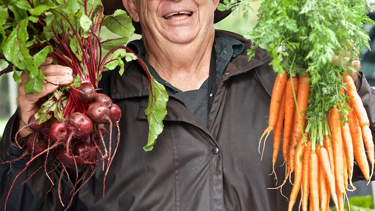JPFM Stall holder holding up freshly picked carrots and beetroots