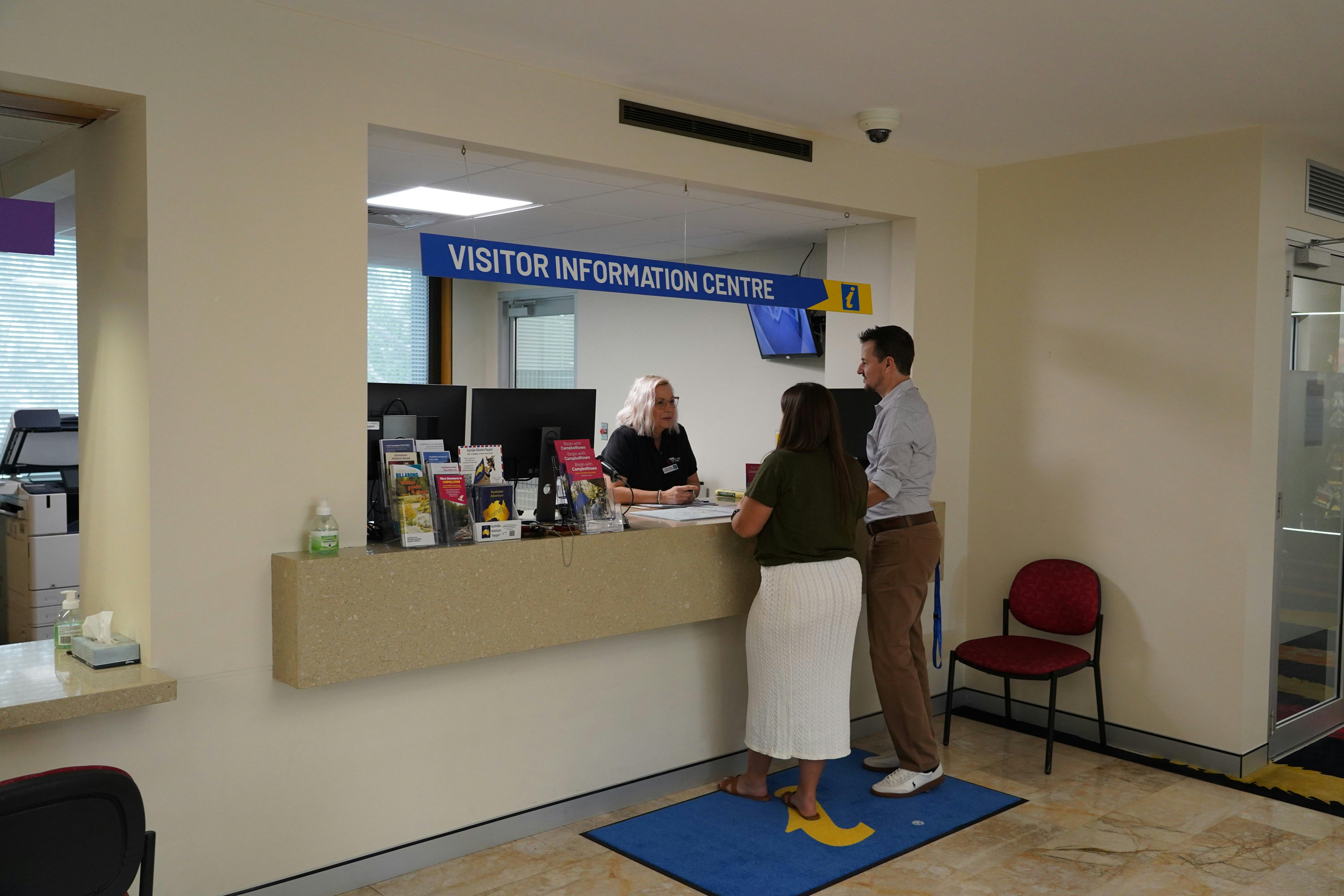 Two people at a counter speaking to another person behind the counter.