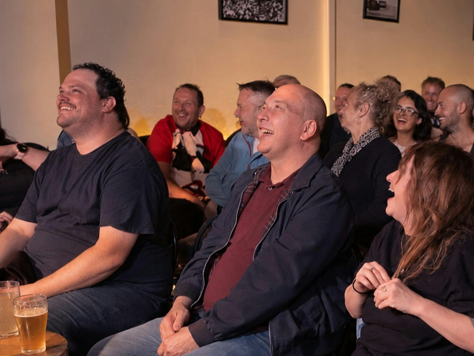 Smiling audience members watching a live comedy performance