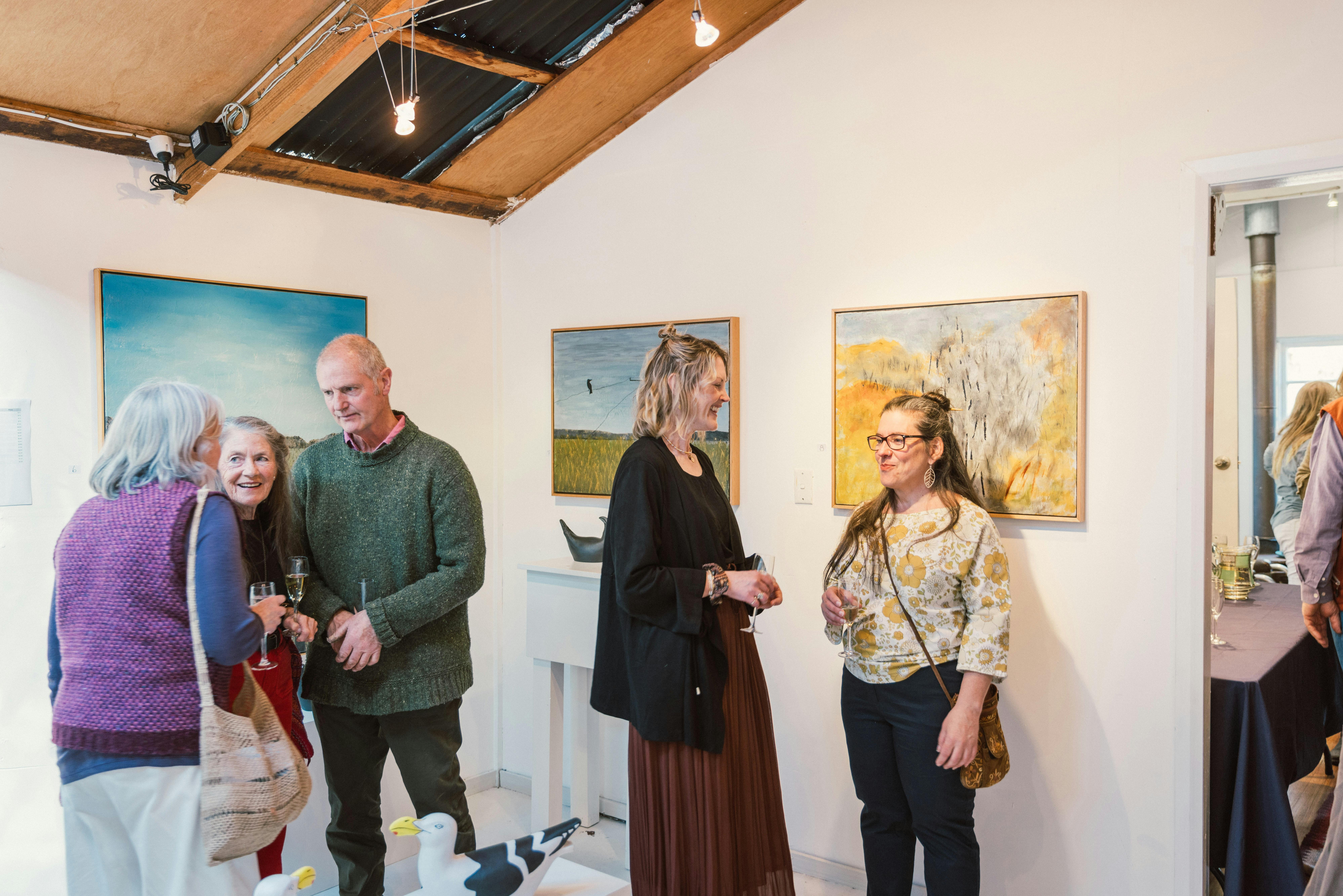 People chatting with artworks on the walls behind them.