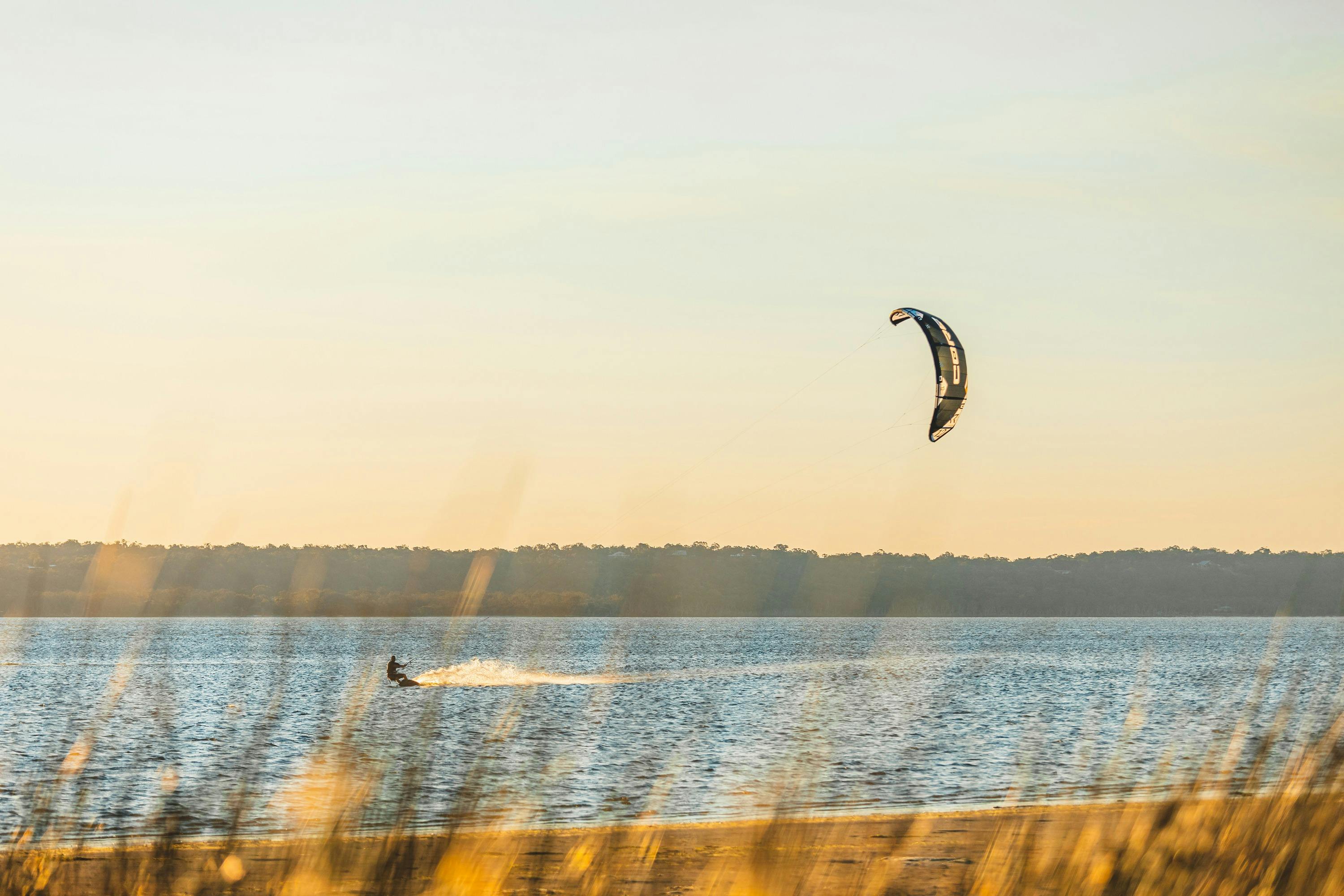A man kite surfing on the water at sunset at Herron Point Campground