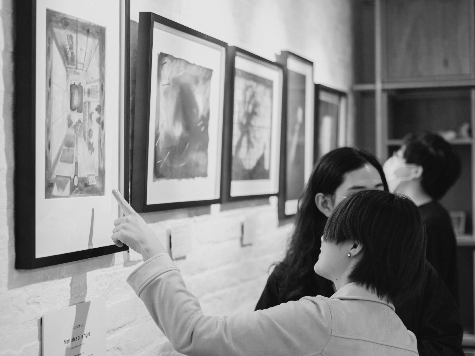 A young person examines a painting on display. The image is in black and white