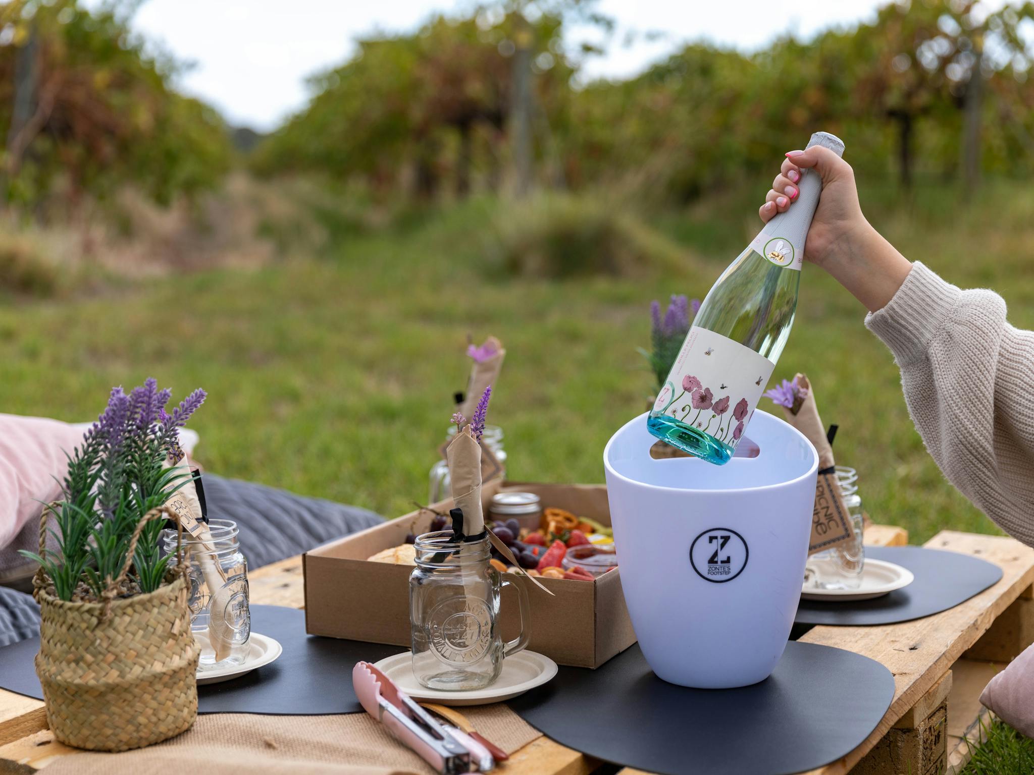 Picnic table with woman taking Prosecco bottle out of white ice bucket with Zontes circle logo on it