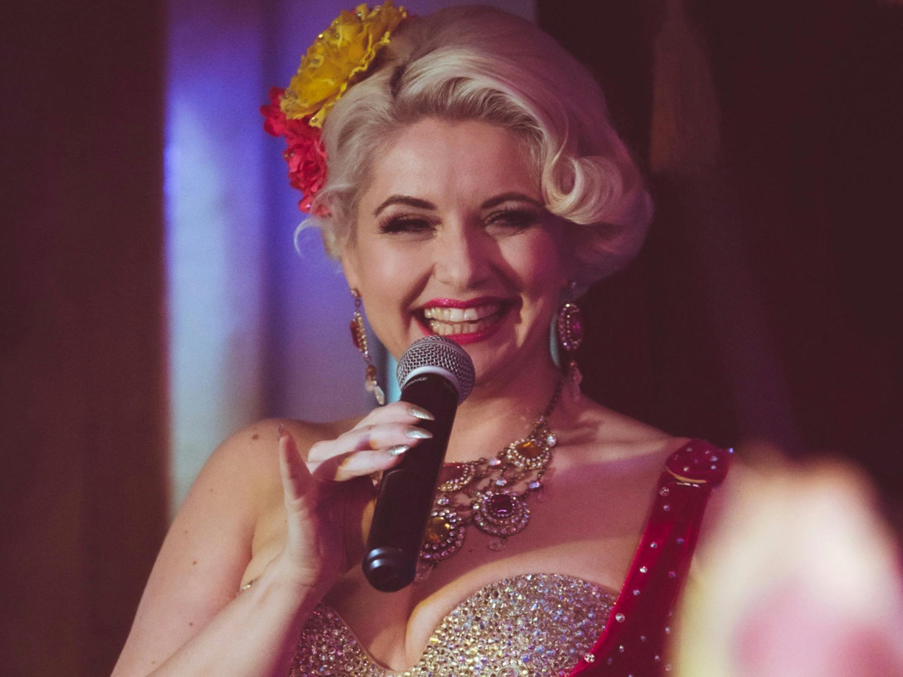 MC Poppy Cherry with a microphone, laughing.