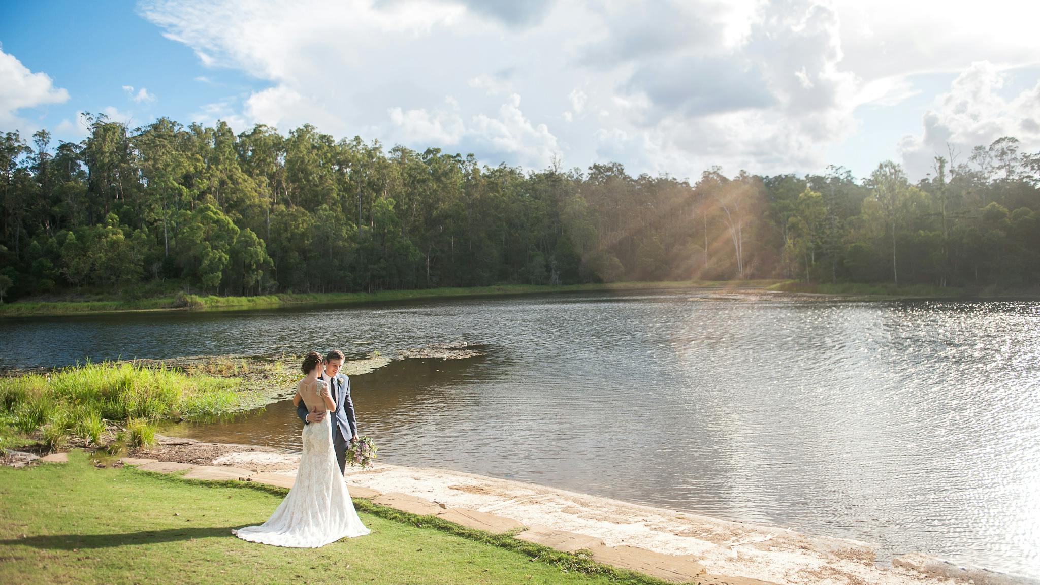 Bride and groom standing by the lake