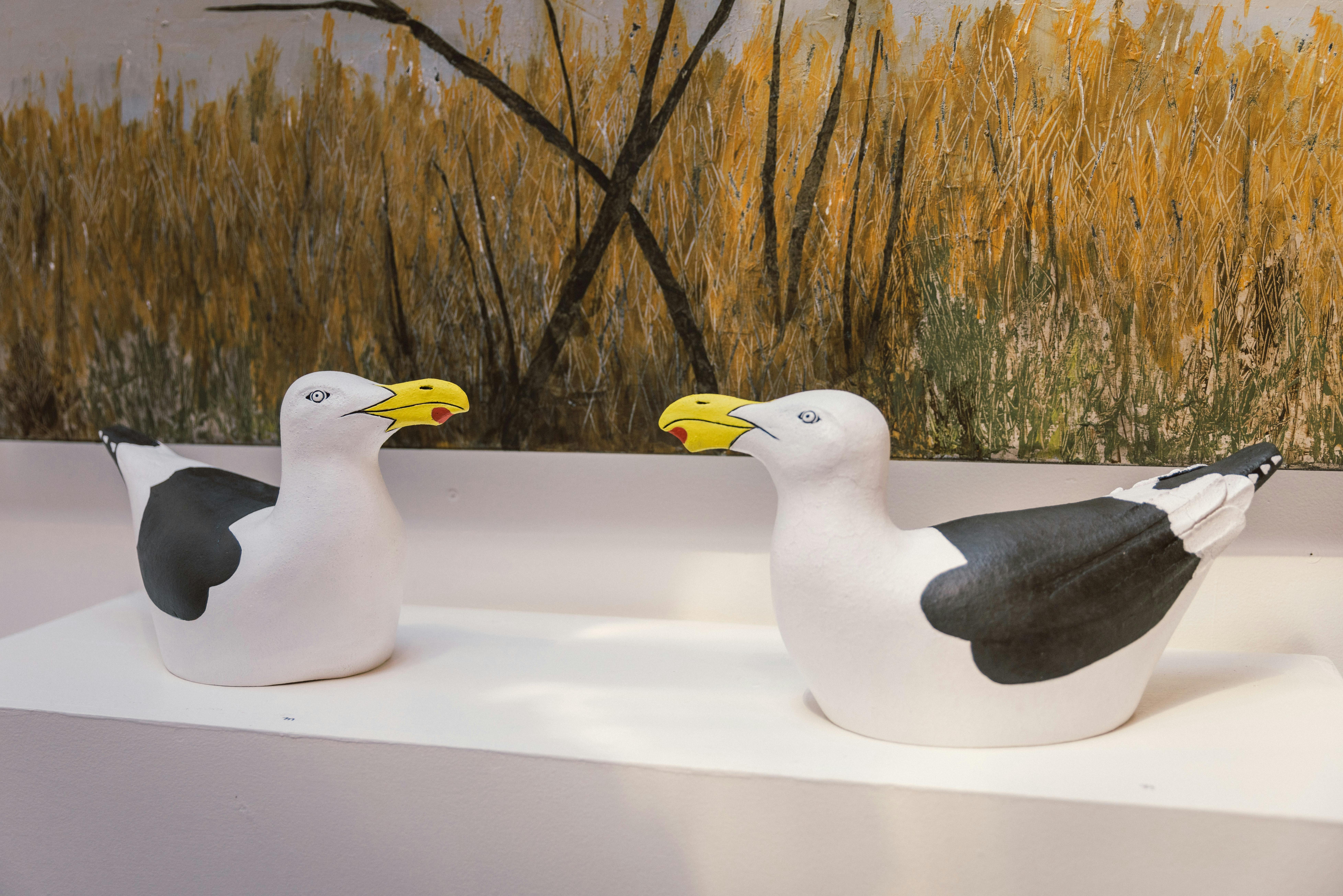 Two ceramic seagulls on a plinth.