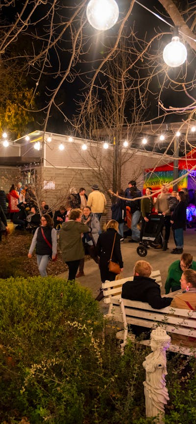 Canberra Potters courtyard at night, with crowds of people and bright coloured and festoon lighting