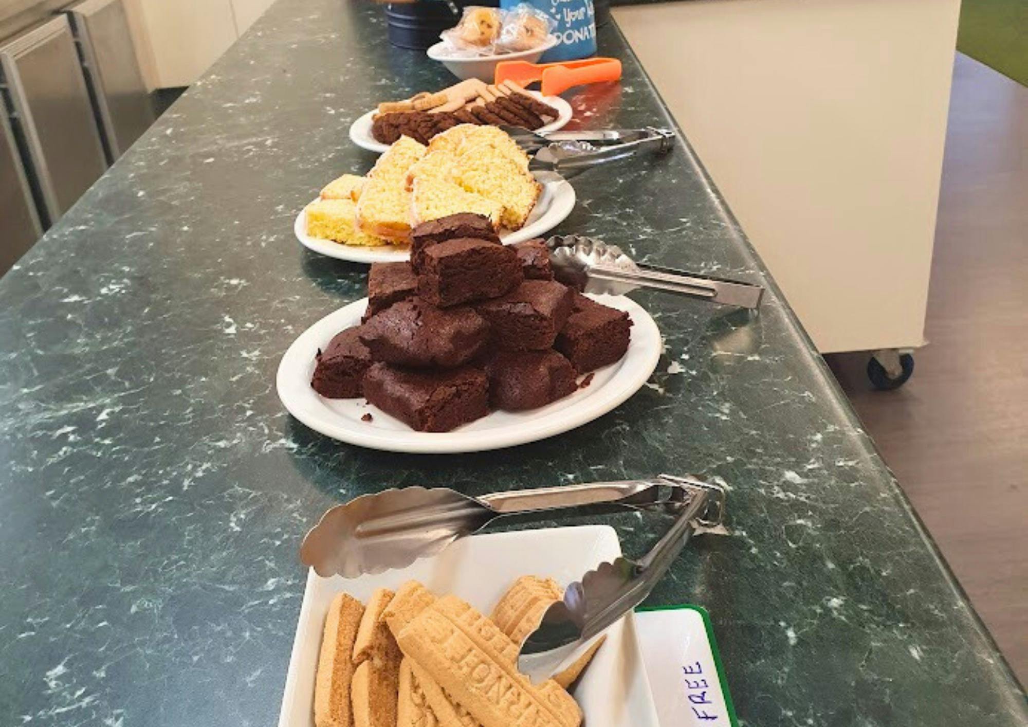 row of plates with various baked goods (e.g. brownies, cake, biscuits etc.)