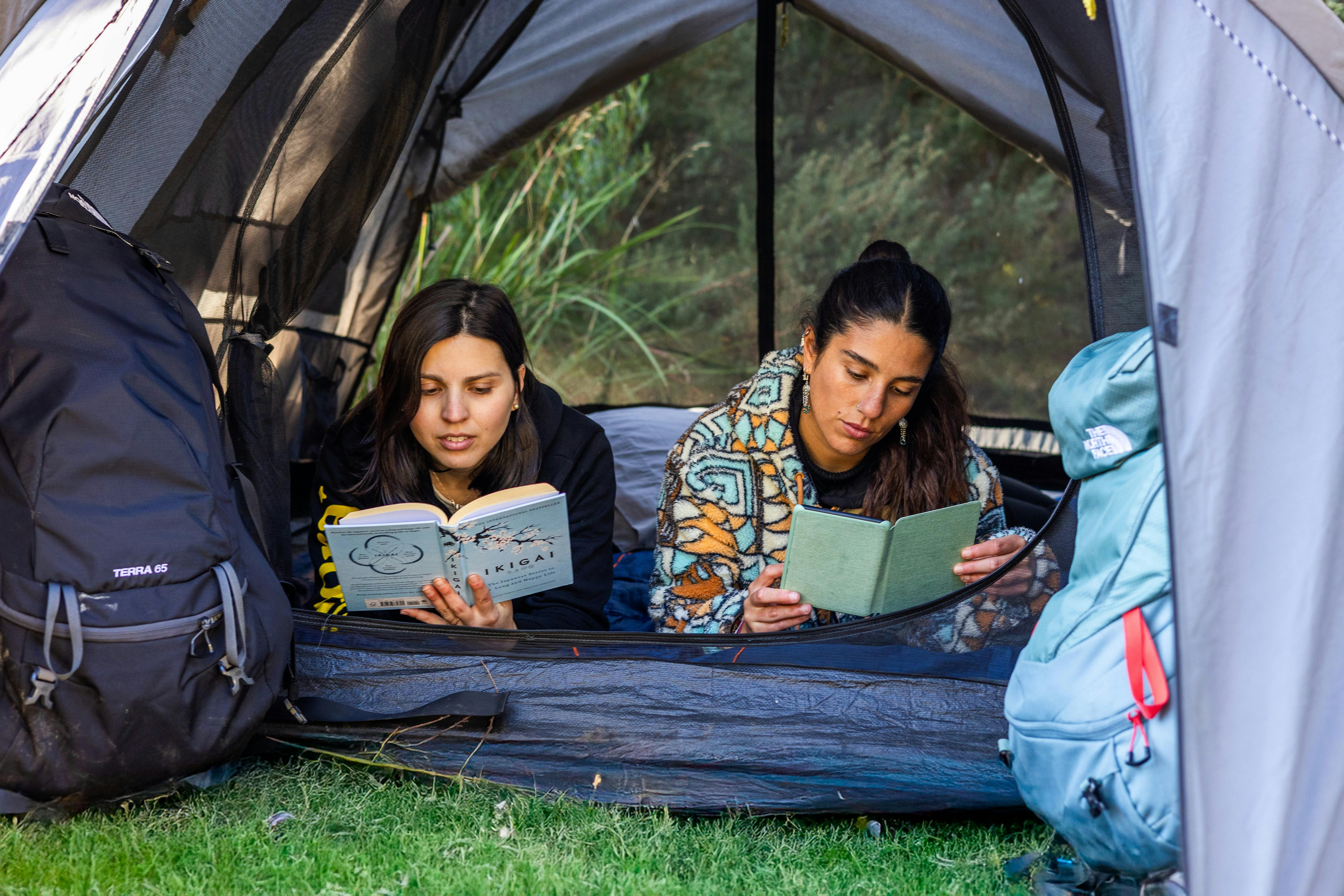 Two friends reading and enjoying their camping time