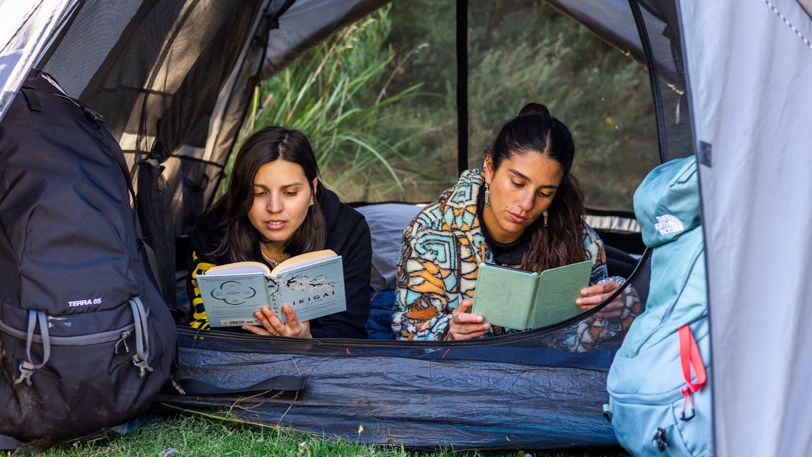 Two friends reading and enjoying their camping time