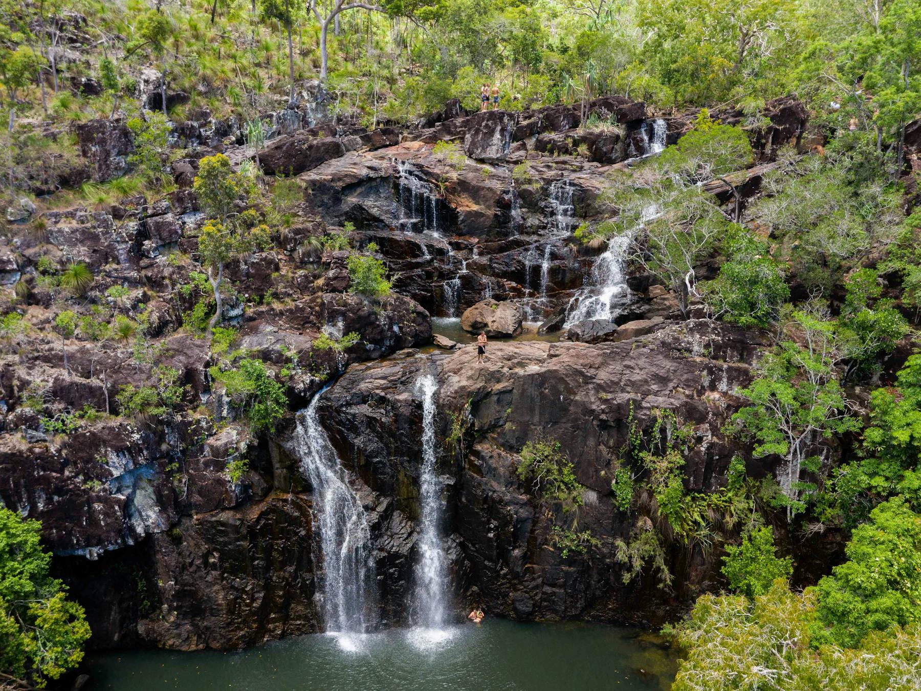 People enjoying the water falling from the many rockpools at the Cedar Creek Falls