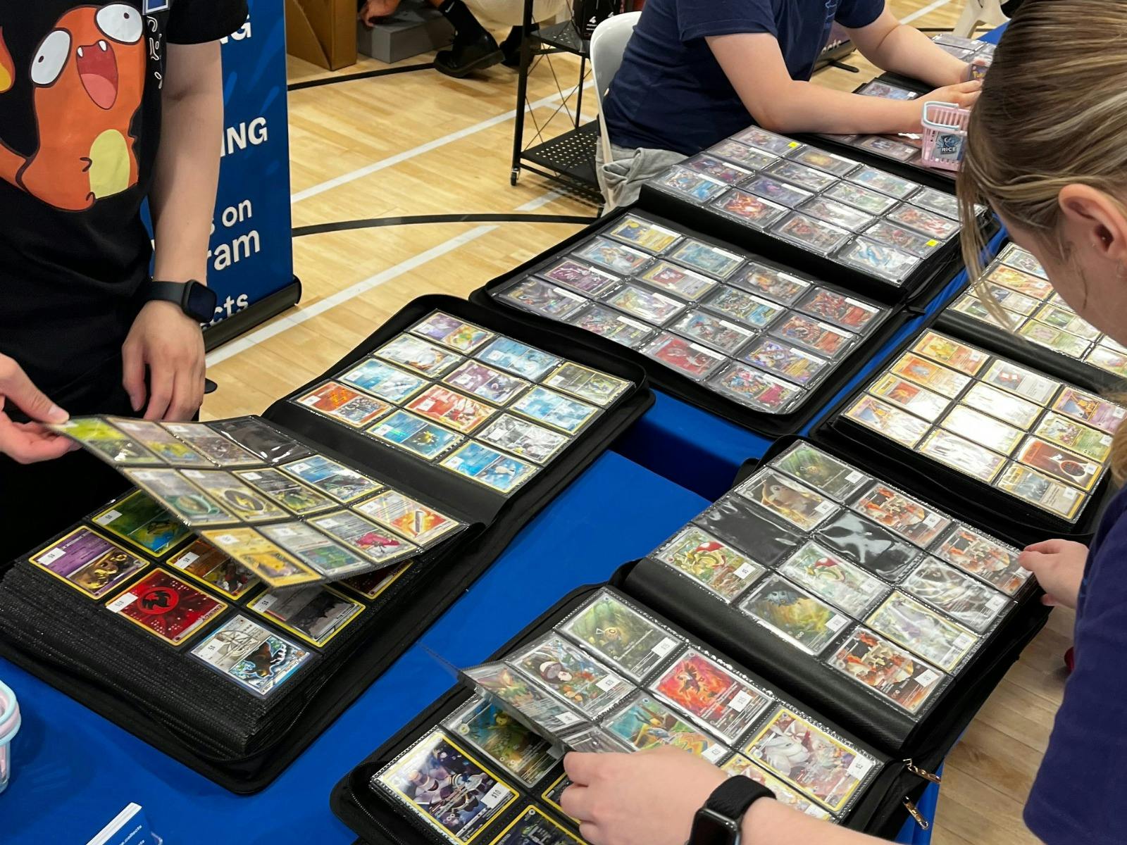 People looking through binders with single trading cards
