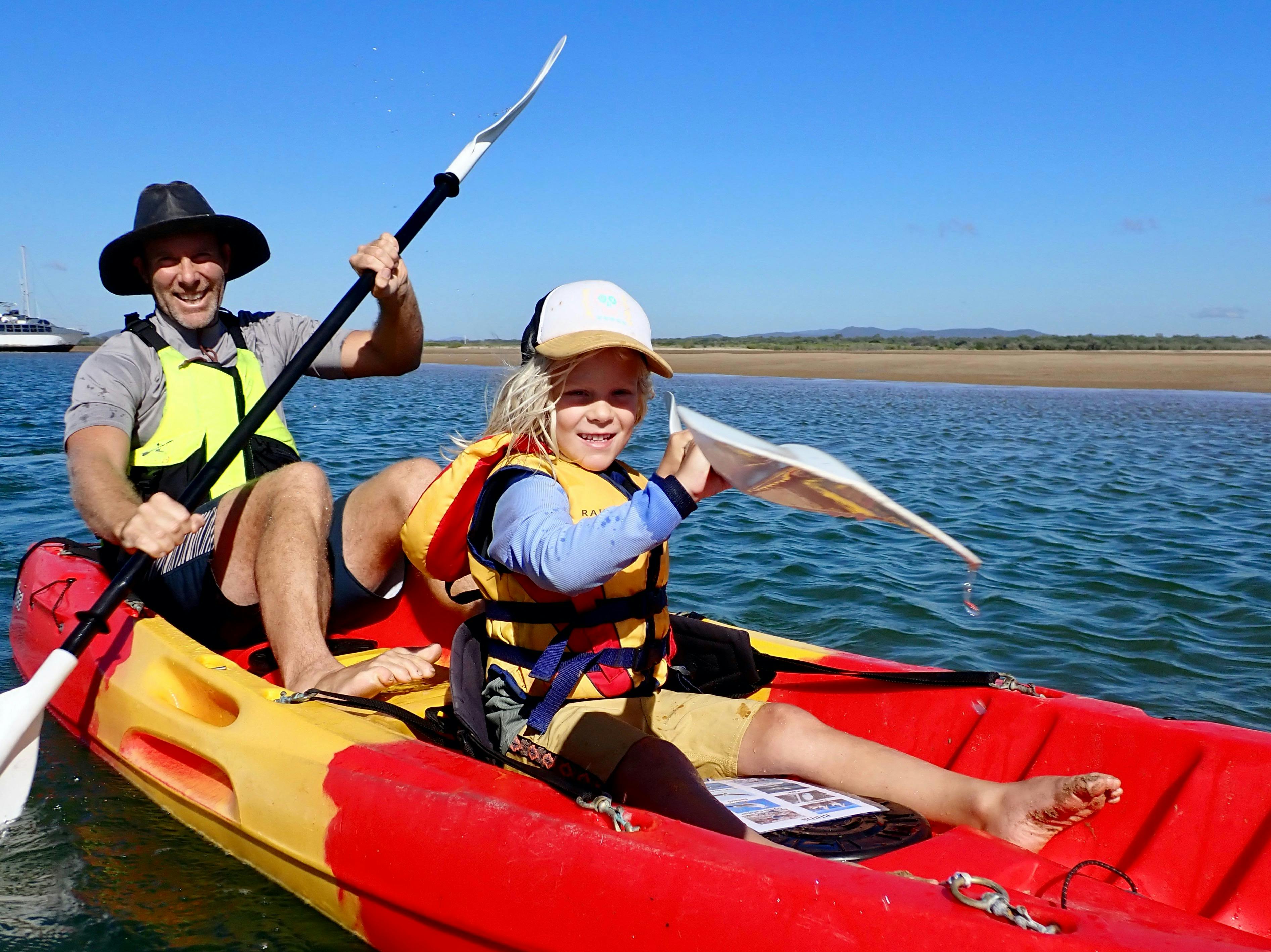 Father and child in a double kayak. Calm water and blue skies