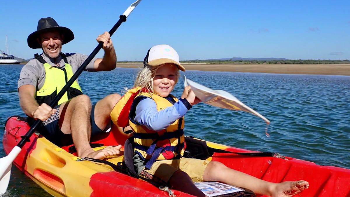 Father and child in a double kayak. Calm water and blue skies