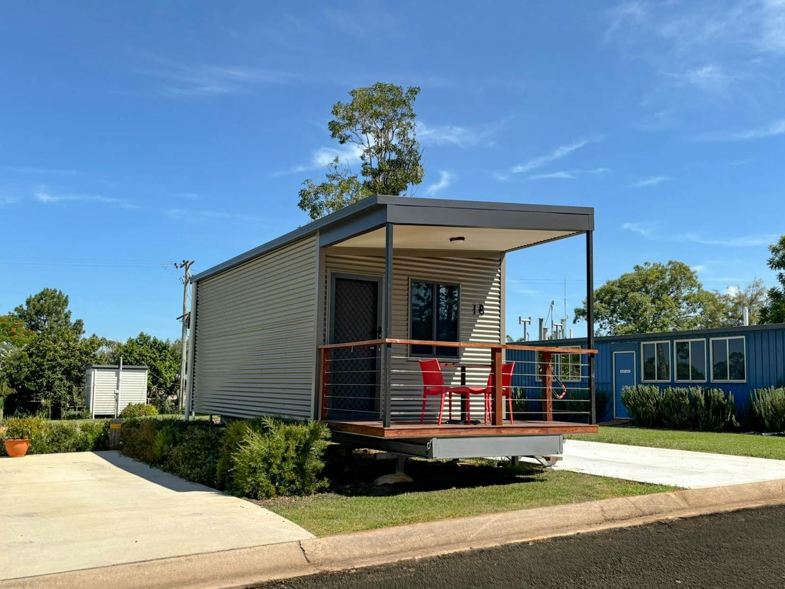Premium Cabin exterior with covered timber deck and red outdoor chairs at Yarraman Caravan Park. Premium Cabin exterior with covered timber deck and red outdoor chairs at Yarraman Caravan Park.