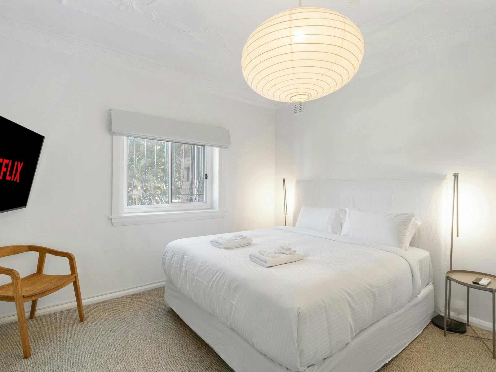 Bedroom with a TV, Netflix display, and calming natural light.