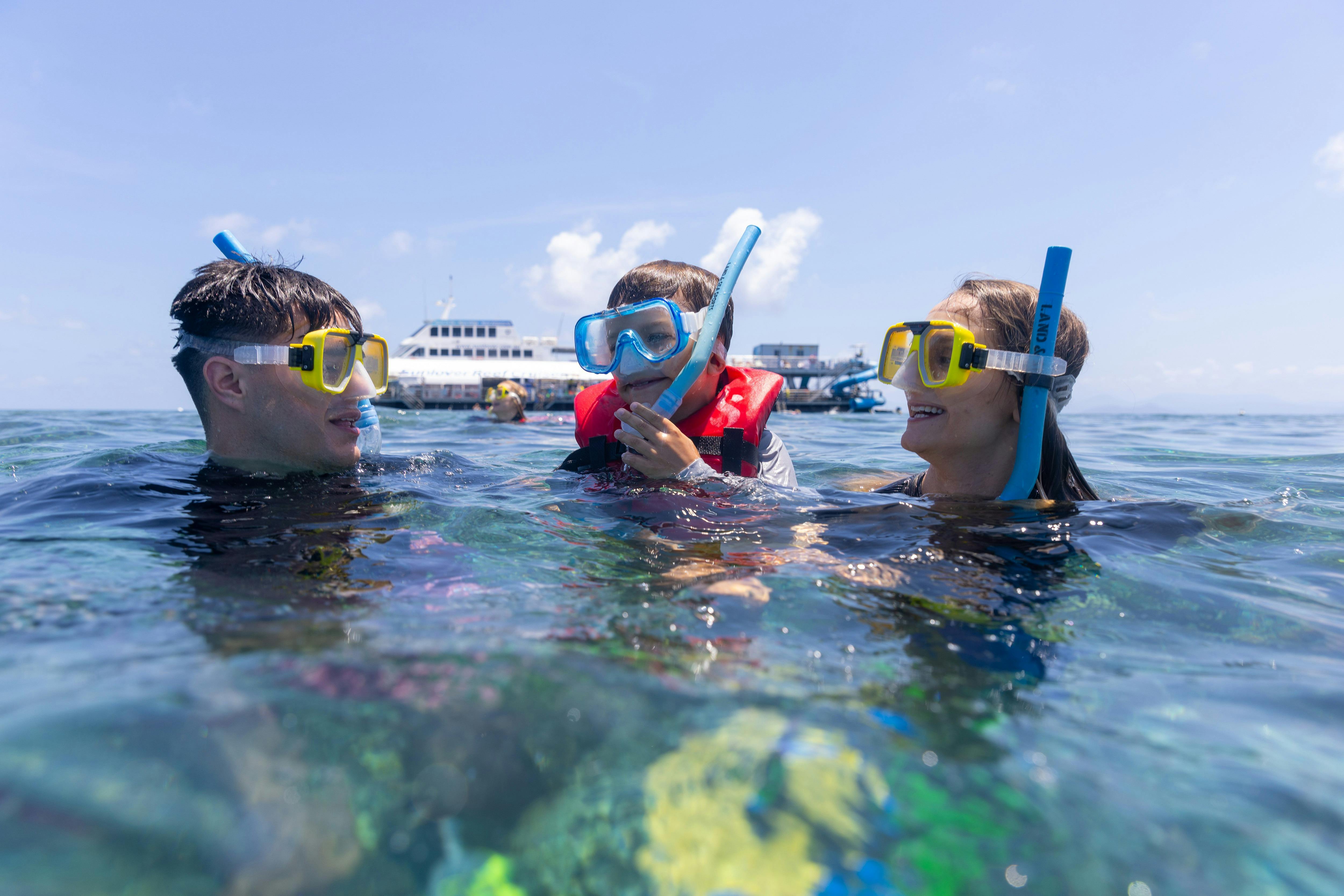 Family snorkeling in Moore Reef with Sunlover Reef Cruises’ pontoon in the background