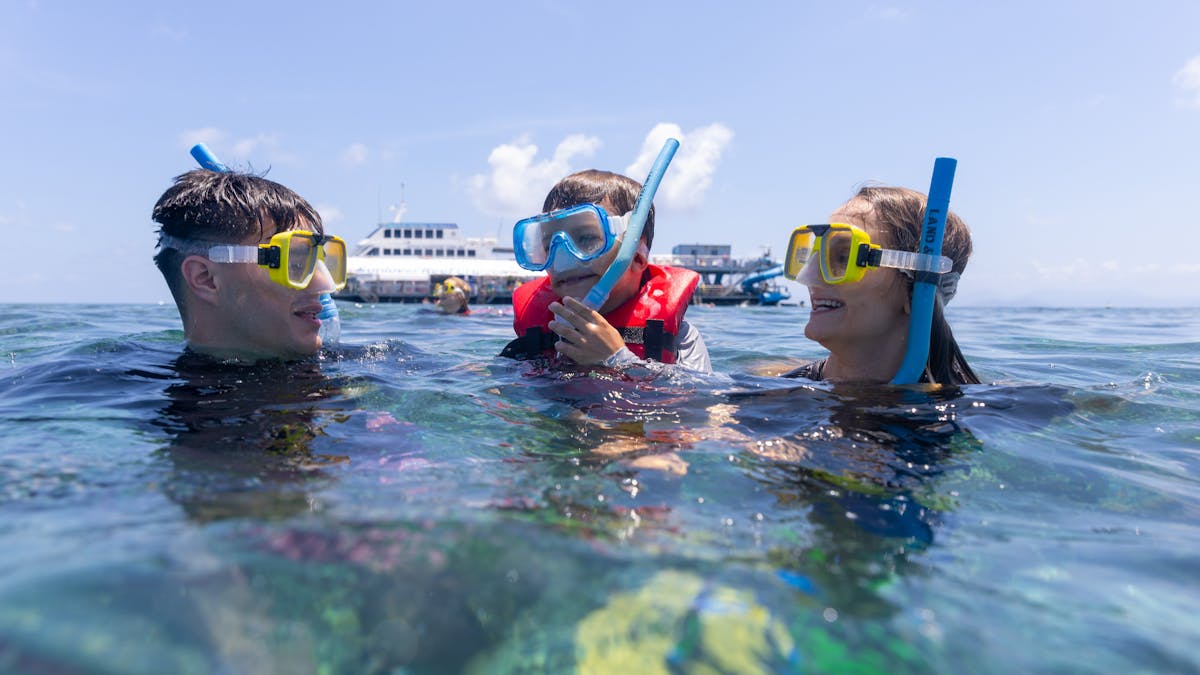 Family snorkeling in Moore Reef with Sunlover Reef Cruises’ pontoon in the background