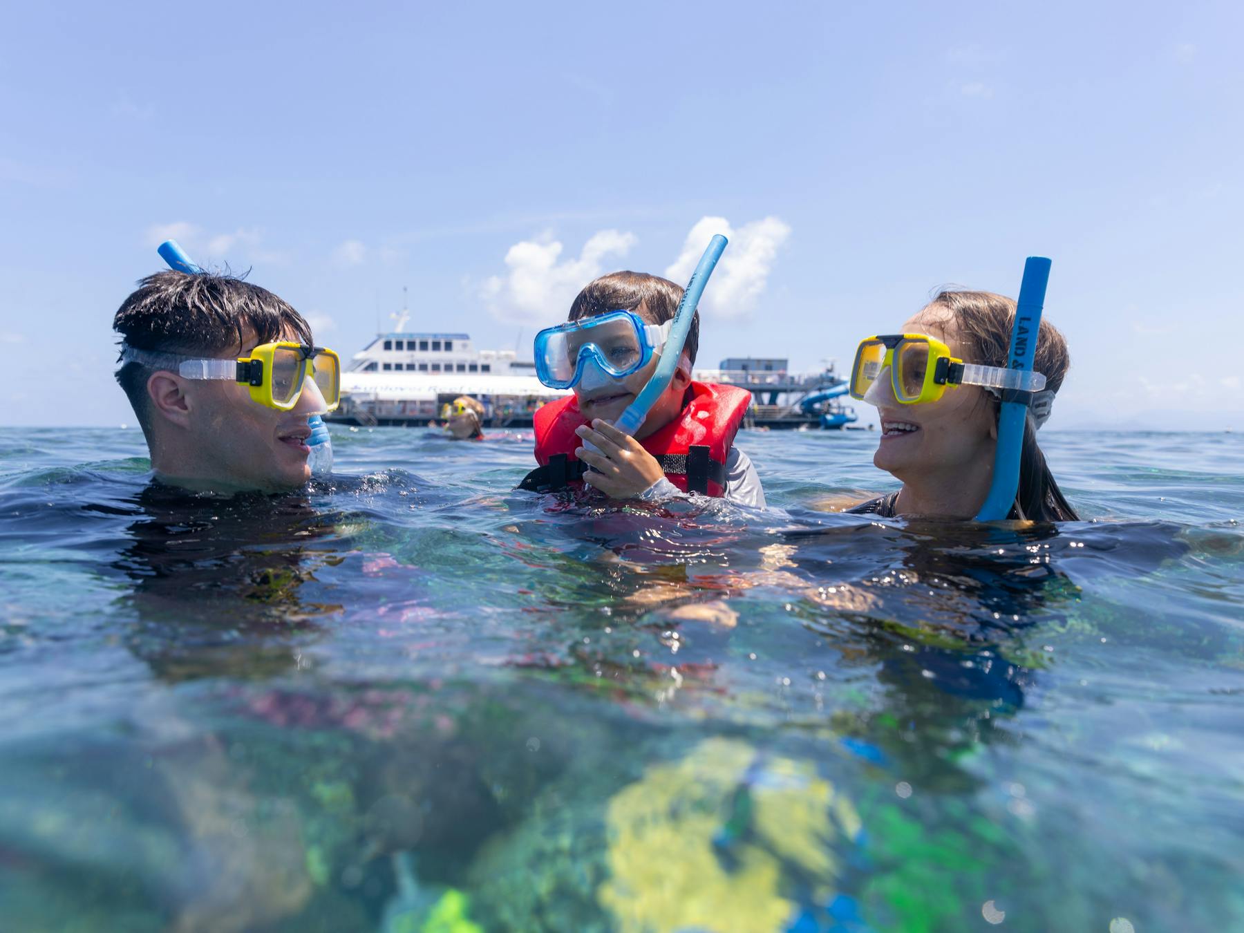 Family snorkeling in Moore Reef with Sunlover Reef Cruises’ pontoon in the background