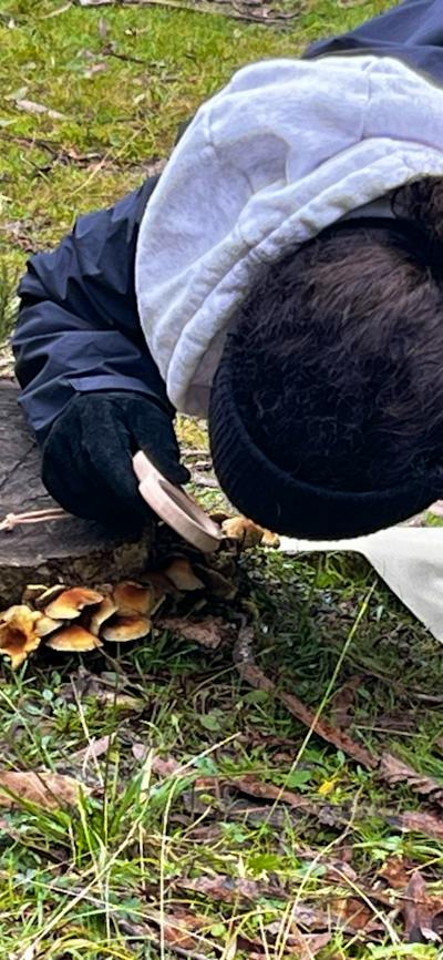 Woman exploring tiny details in nature with magnifying glass