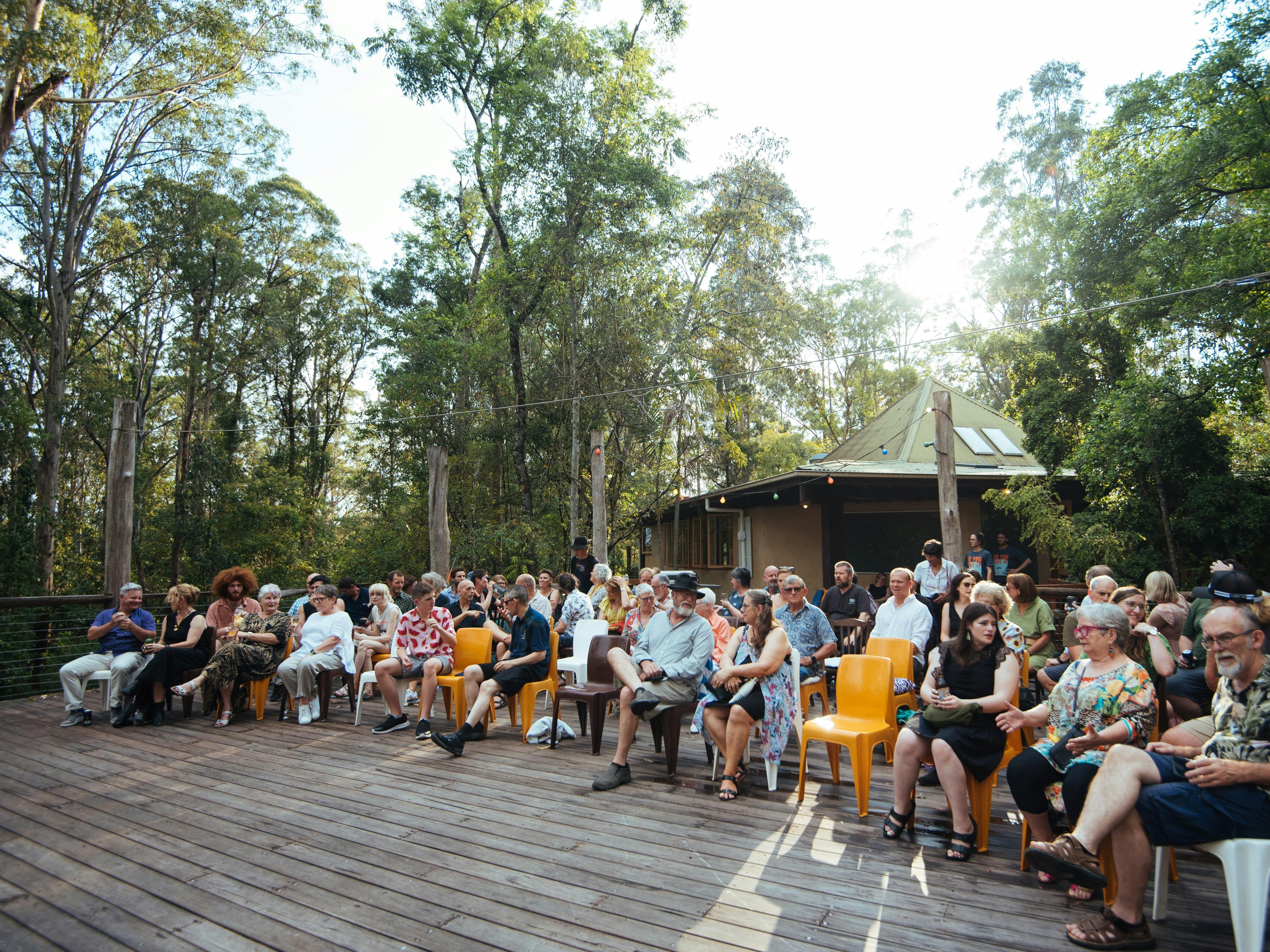 Group of people sitting on large open deck surrounded by forest at Wangat Lodge