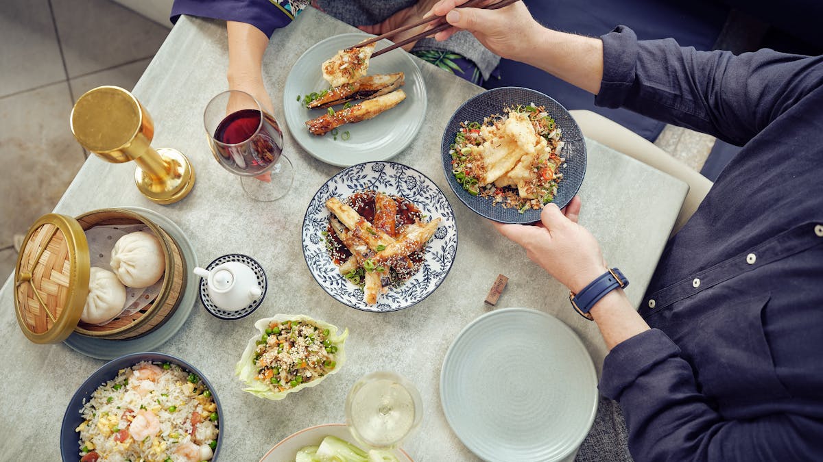 Birds eye photo of a man serving a woman some fried rice at a table with many food options.