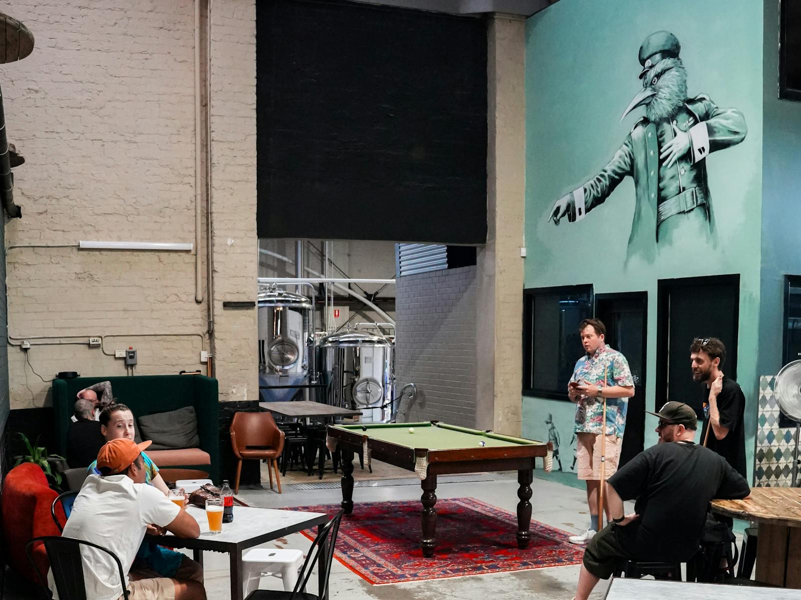 A mural of one of our bird characters pointing towards the brewery