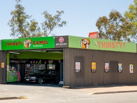 Thirsty Camel Bottleshop with vibrant green signage and a drive-through entrance.