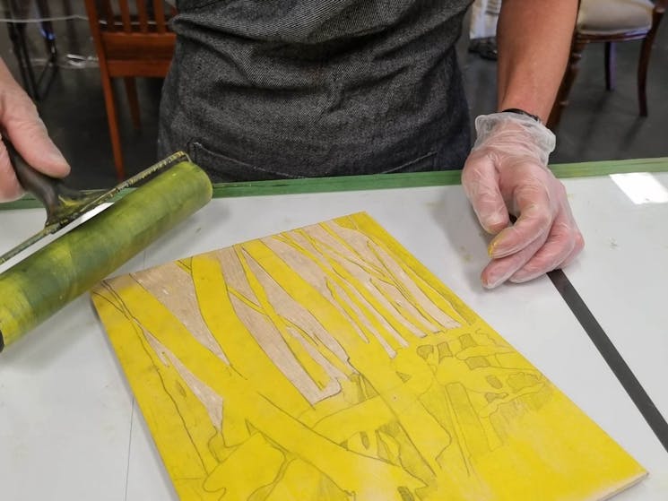 artist rolling bright yellow ink onto a woodcut block