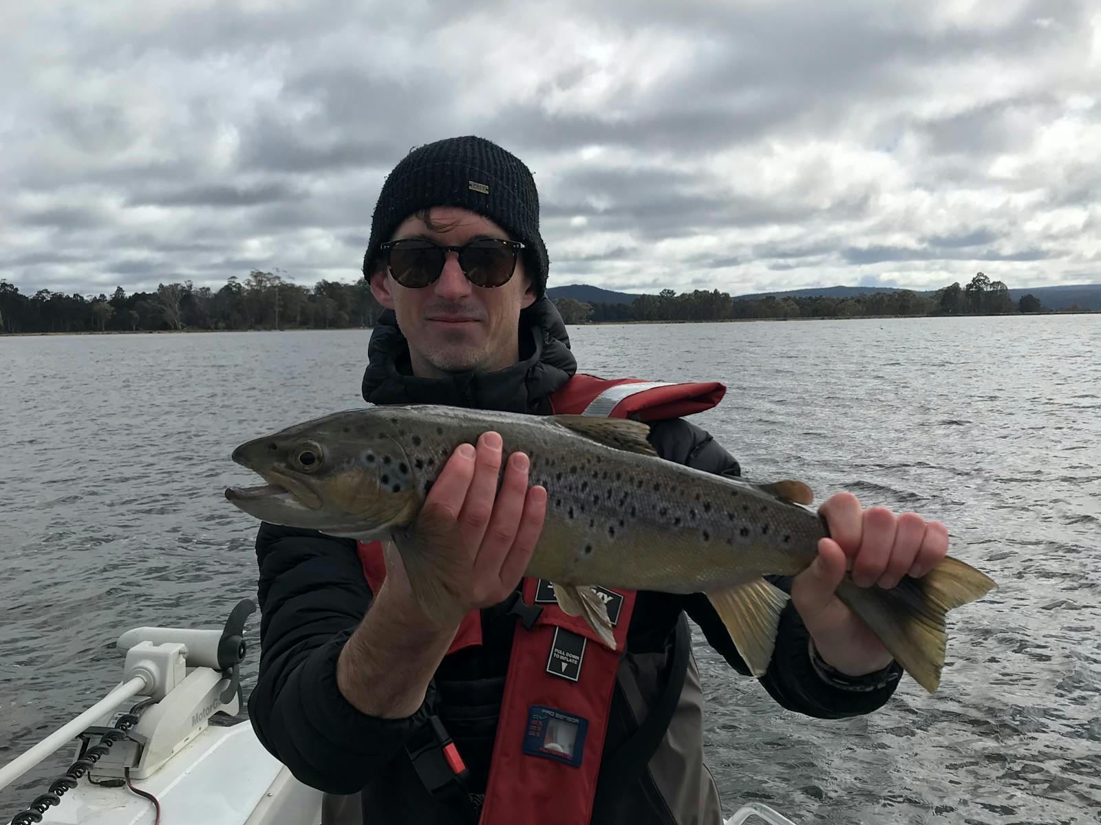 Man in beanie holding large trout