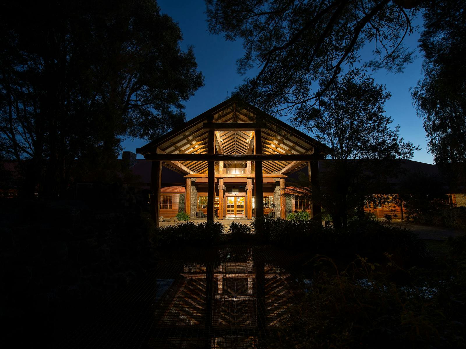 The main entry to Tall Timbers glows with the surrounding trees silhouetted in the eveningsky