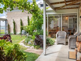 A grassed courtyard with seating areas and planting,  Beautiful stone walls surround the space.