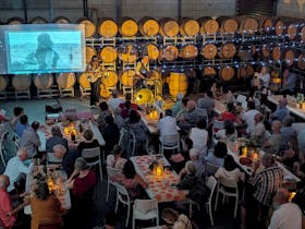 Crowd of people sit in barrel hall with fairy lights