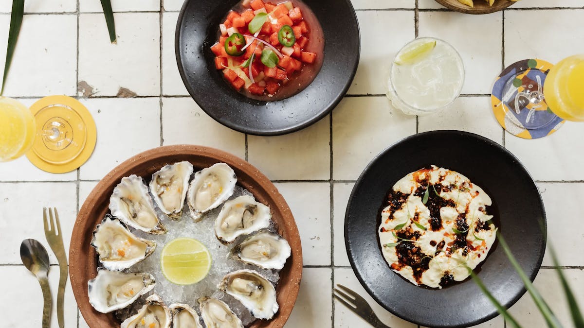 Oysters and a spread of food on a white tiled table