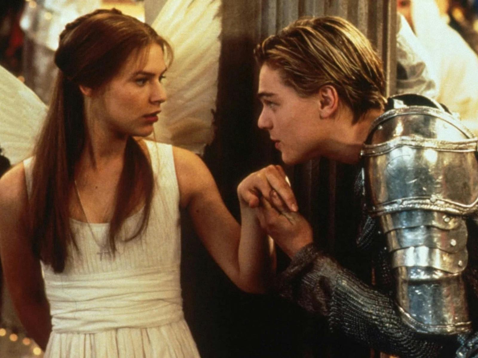 Woman dressed as angel and man dressed in armour kissing her hand