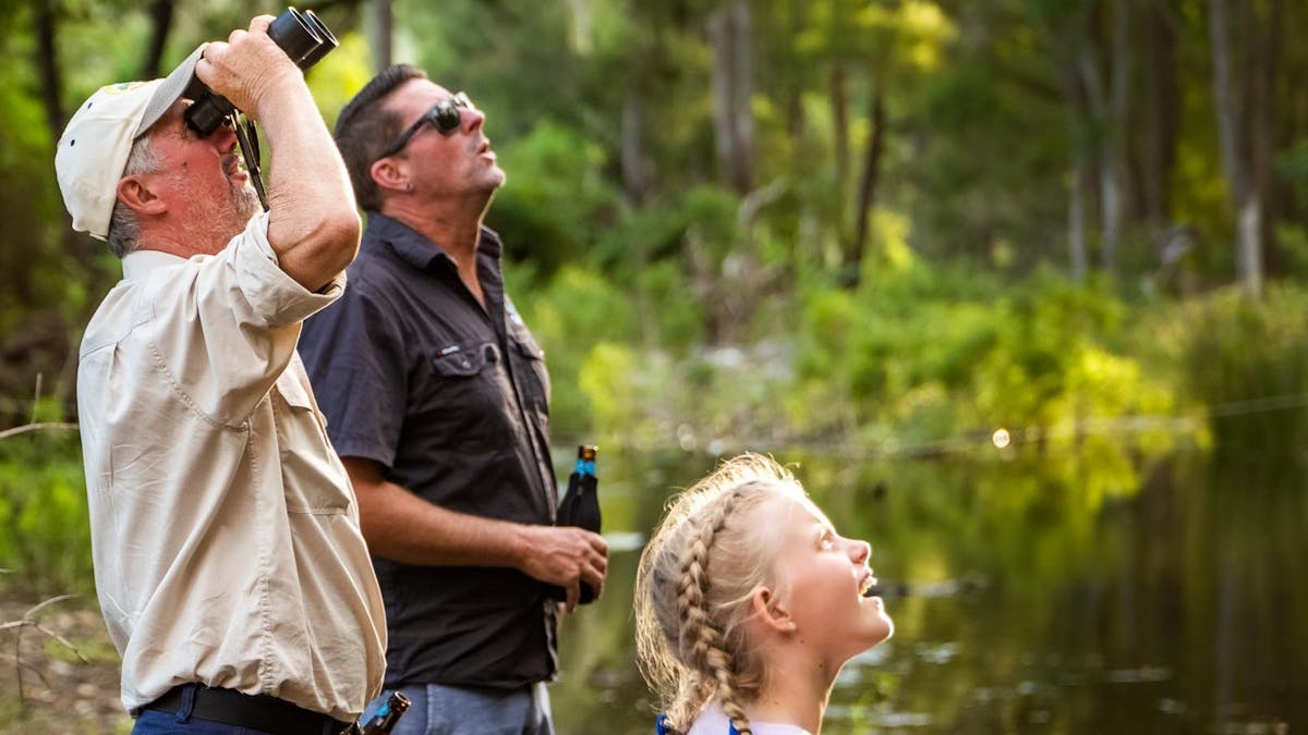 Don't forget the binoculars! A group of people looking through binoculars to see birds.