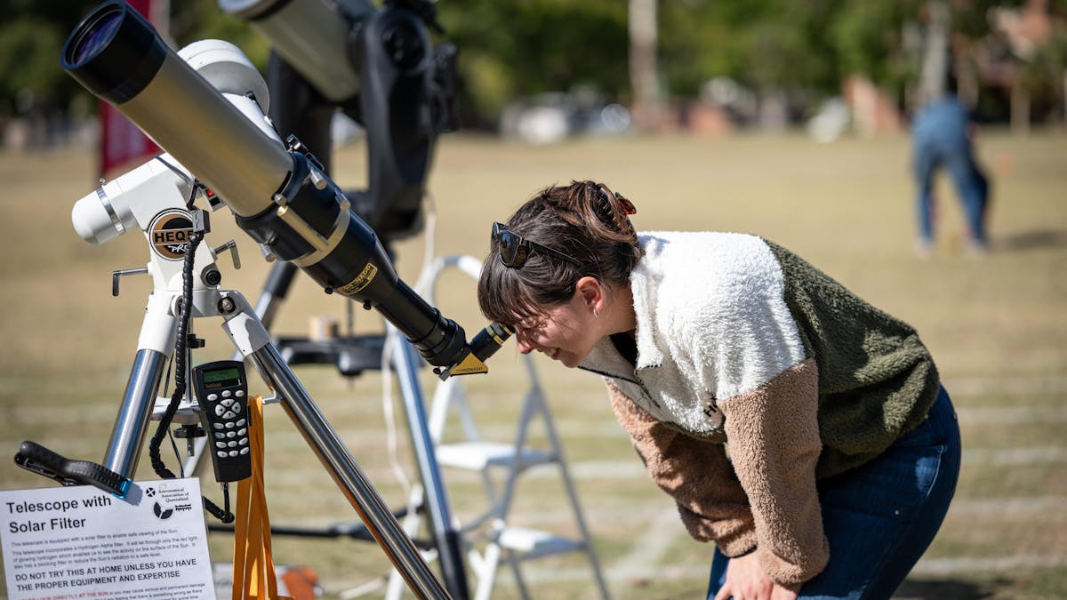 A lady looks through a solar telescope in broad daylight
