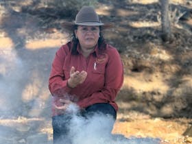 Sitting in a creek bed; in front of a smoking ceremony