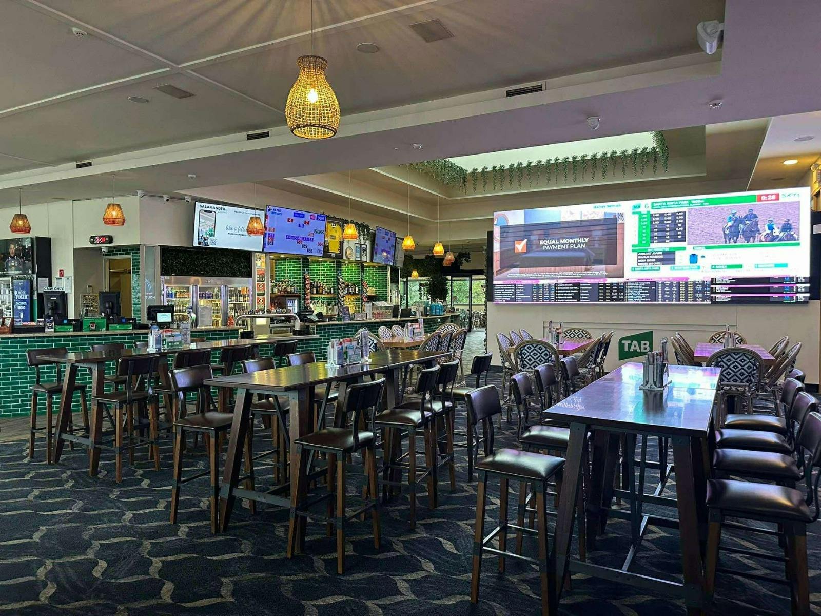 sports bar area at a venue with large screens to watch sport and seating areas to eat and drink