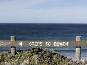 Wooden sign that says steps to beach with an arrow pointing right to show the direction to the beach