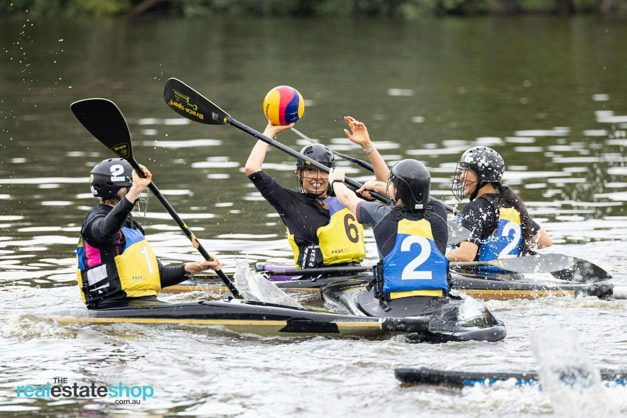 Four players are on the field. One woman (yellow team) is ready to throw the ball